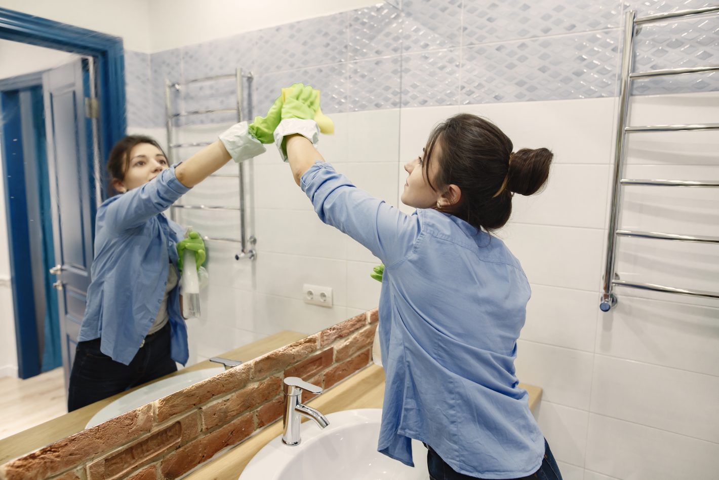 Limpeza do banheiro: confira algumas dicas | Mulher limpando o espelho de um banheiro | Atacadão