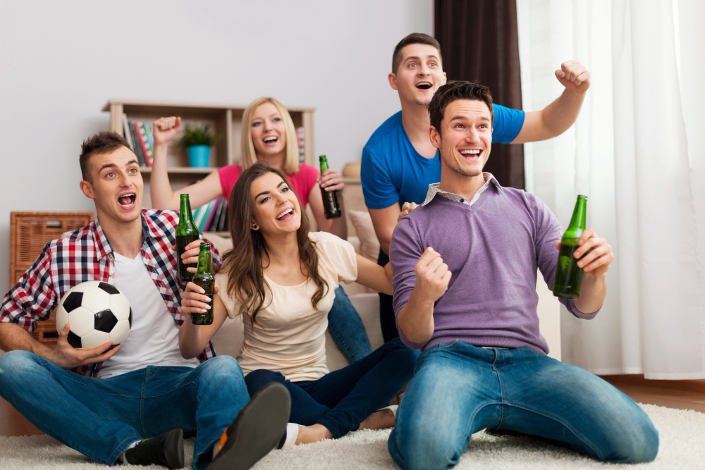 Assistir esportes em casa: dicas para aproveitar | Amigos comemorando com cervejas | Atacadão