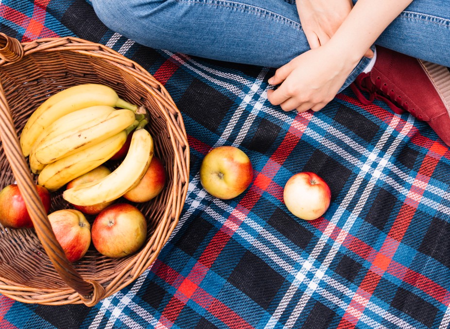 Lista de compras perfeita para um piquenique | Bananas e maças em uma toalha de piquenique | Atacadão