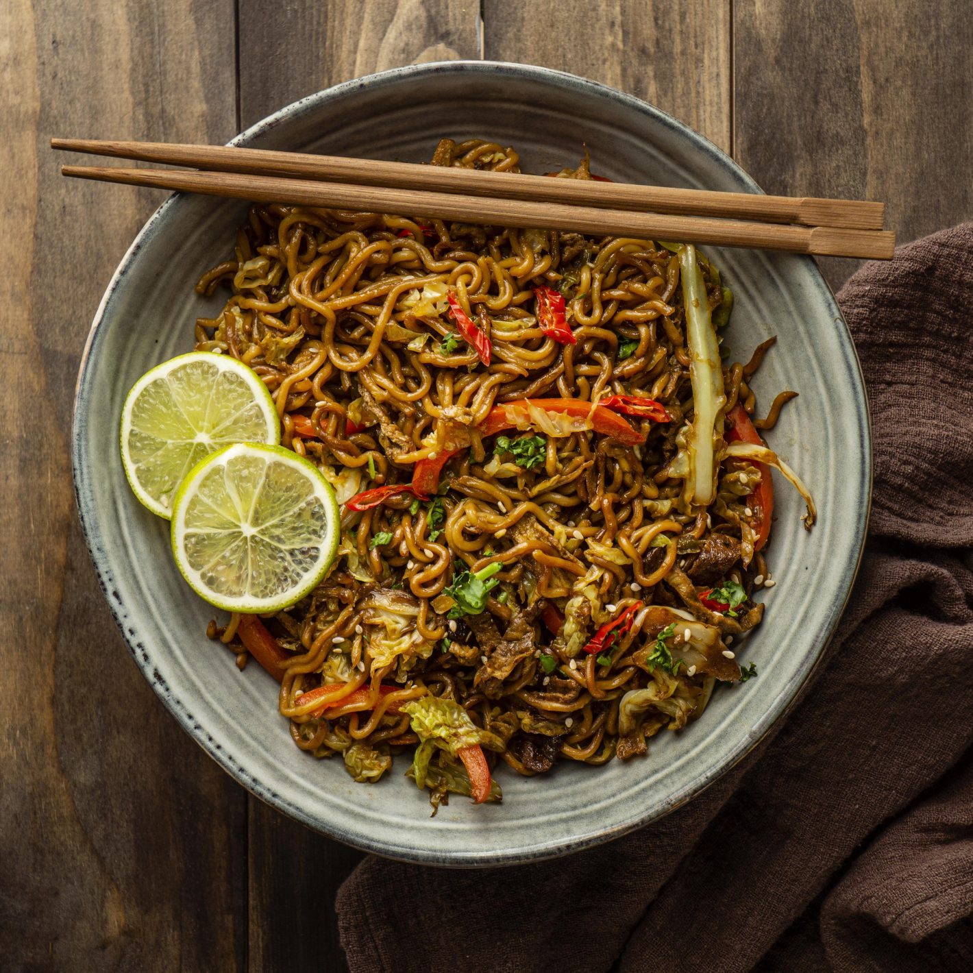 Yakissoba: aprenda receitas com diferentes ingredientes | Foto de cima de um prato de yakissoba e dois raxis | Atacadão