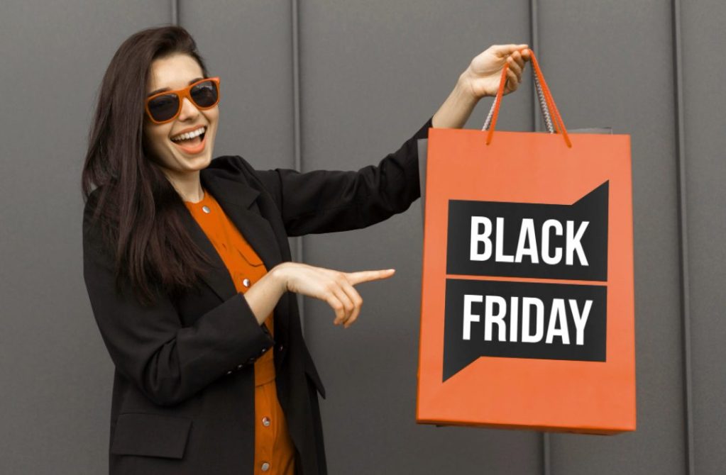 Como funciona a Black Friday? | Mulher apontando para sacola laranja escrita Black Friday | Atacadão