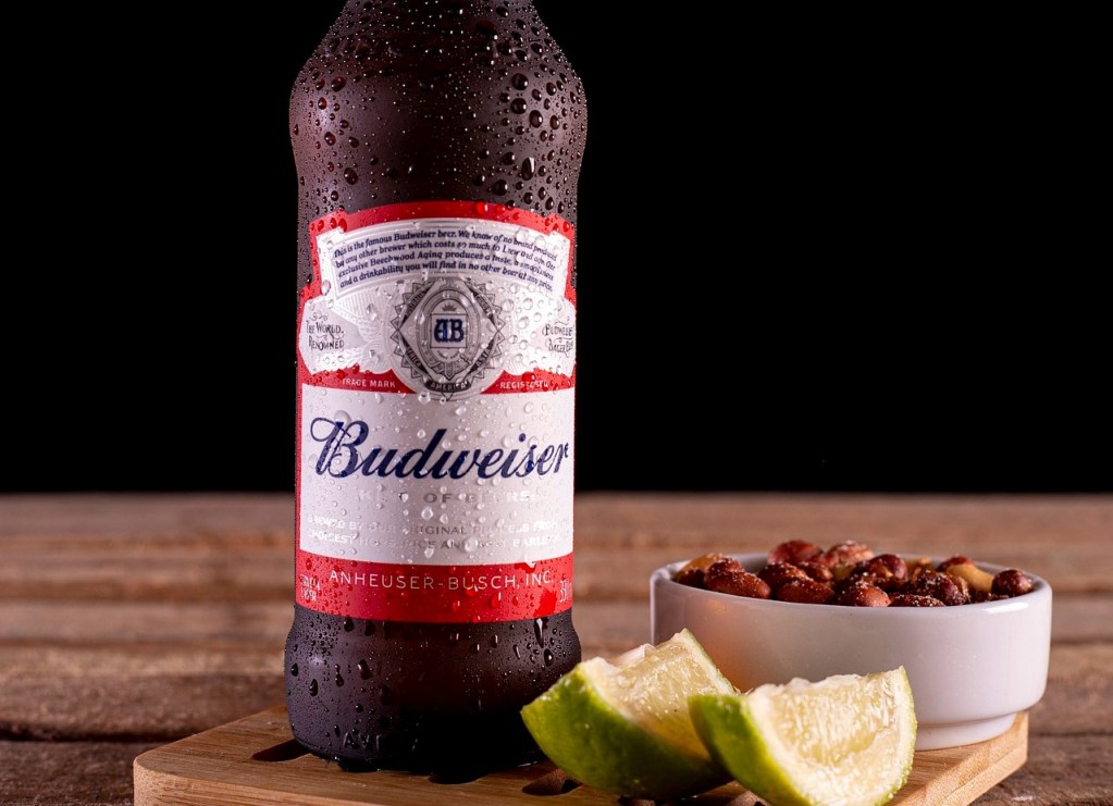 As melhores marcas de cerveja para vender em seu bar | Garrafa de Budweiser ao lado de amendoim e limão | Atacadão