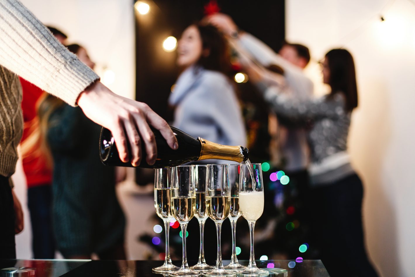 Cardápio para festa de Ano Novo: saiba o que servir | Foto de uma pessoa servindo champagne em uma festa de ano novo | Atacadão