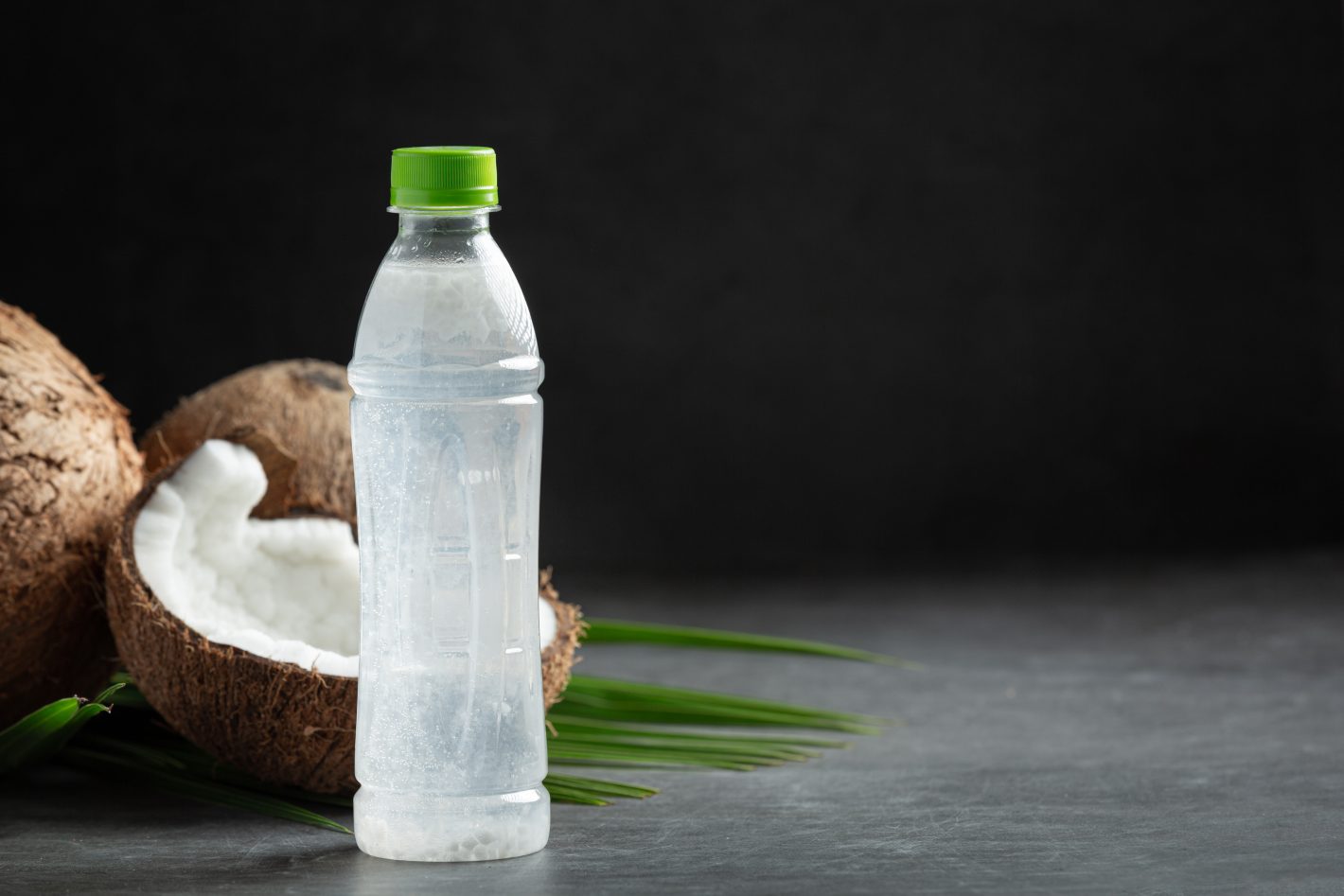 Água mineral e água de coco: conheça as diferença | Foto de uma garrafa com água e coco e um coco cortado ao lado | Atacadão