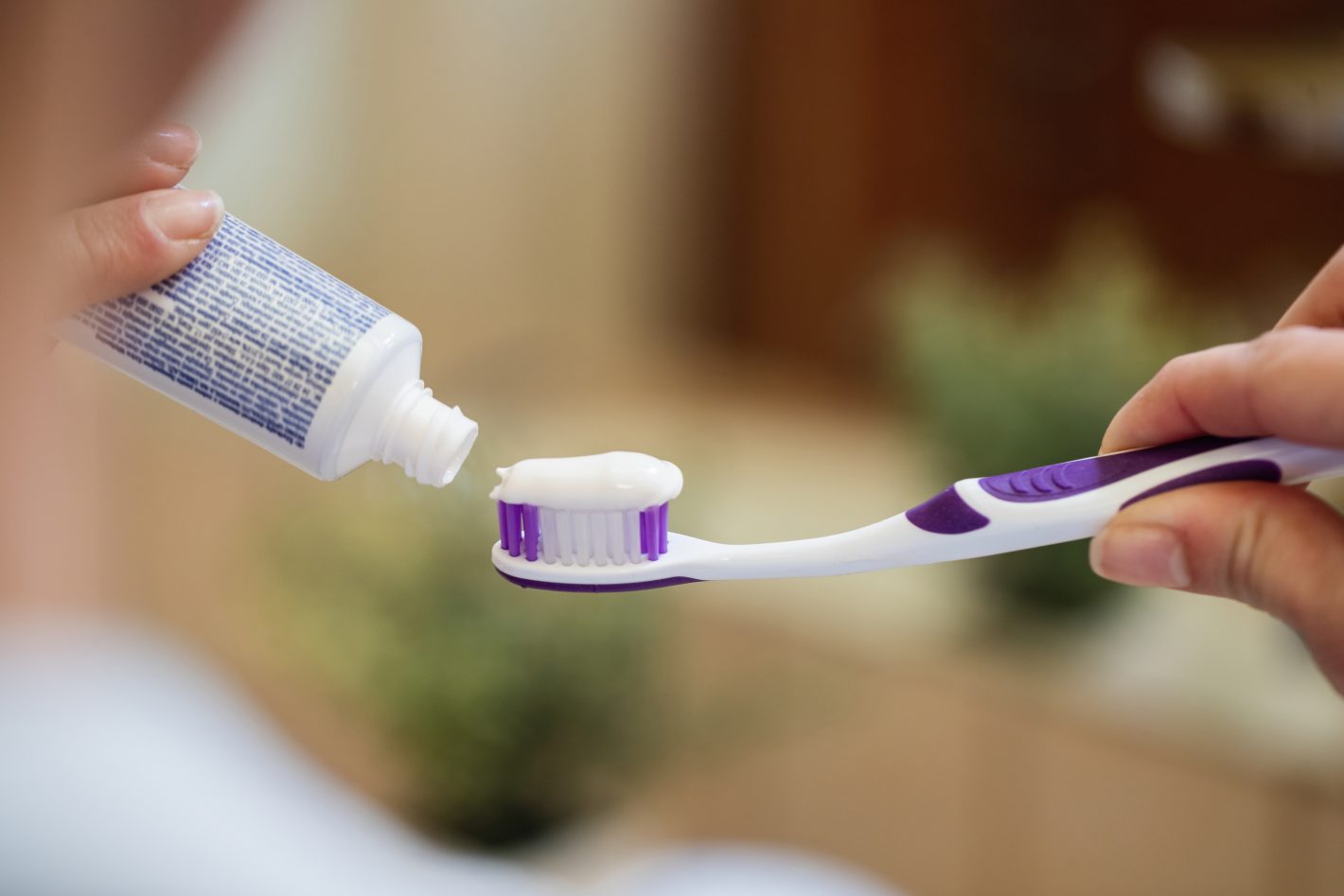 Produtos de higiene para bolsa: saiba o que comprar | Foto de uma mão aplicando creme dental em uma escova de dente | Atacadão