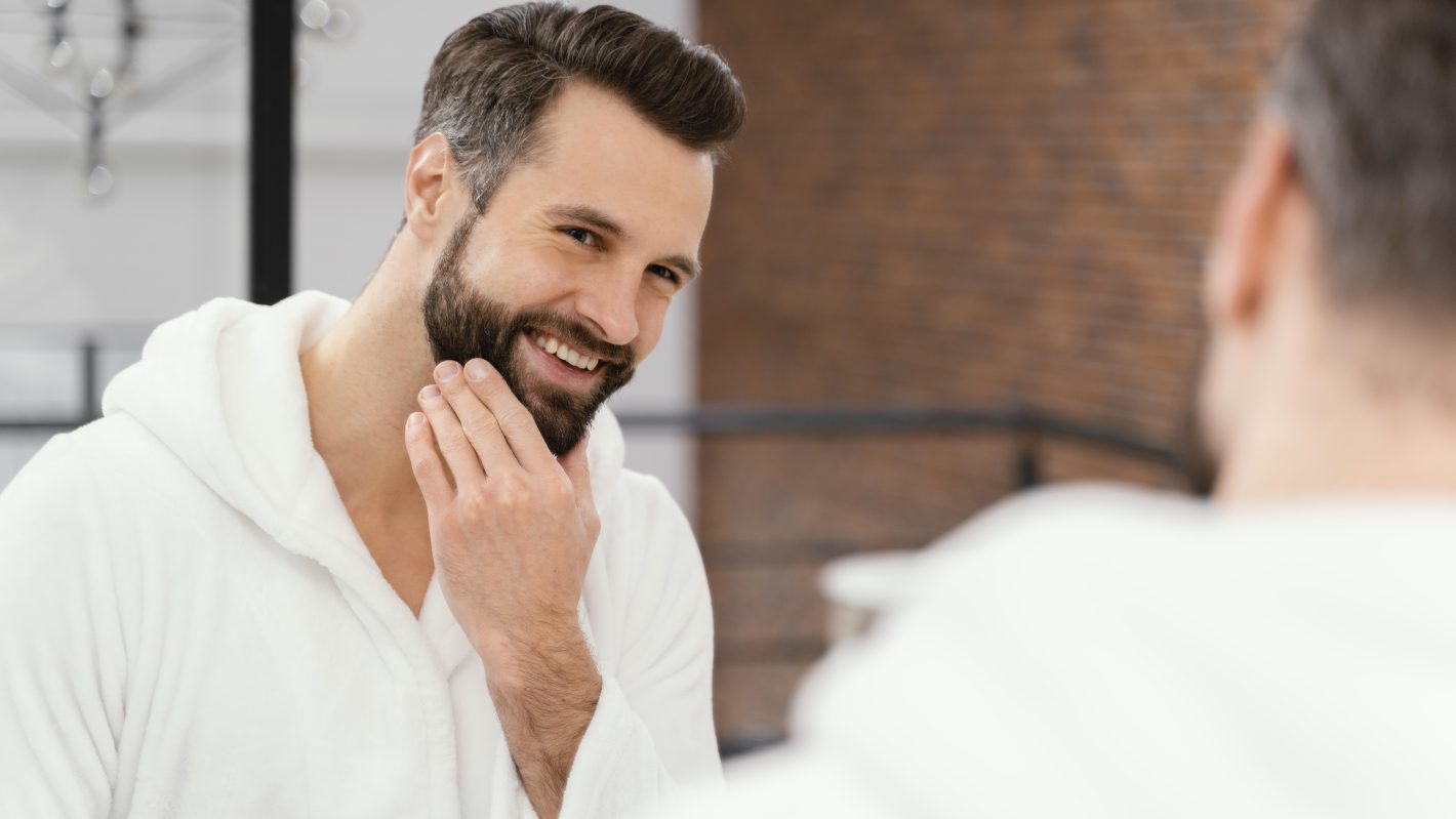Produtos para tirar barba: conheça os melhores | Homem sorrindo no espelho | Atacadão