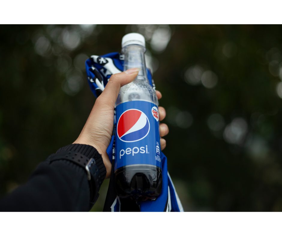 Refrigerantes para aniversário: saiba o que comprar | Foto de uma mão segurando uma garrafa de pepsi | Atacadão