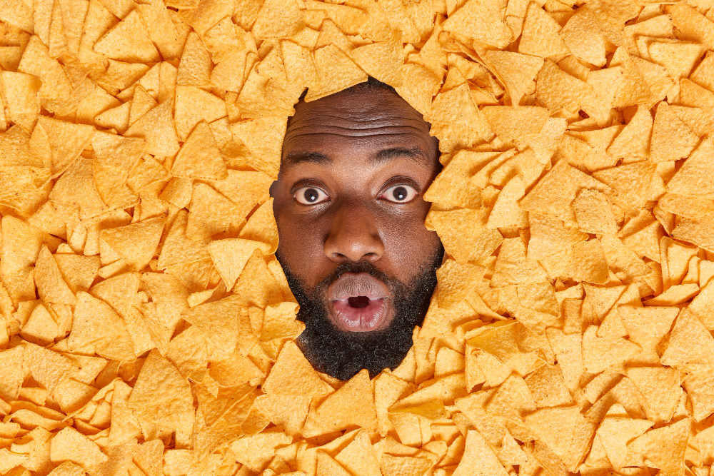 Os melhores sabores de salgadinho para se deliciar | Homem mergulhado em diversos nachos de Doritos | Atacadão