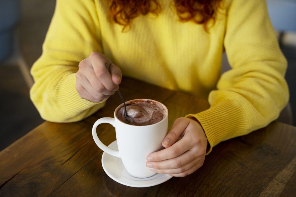 Chocolate quente: dicas para fazer o melhor | Foto de mãos femininas mexendo a colher em uma xícara de chocolate quente | Atacadão