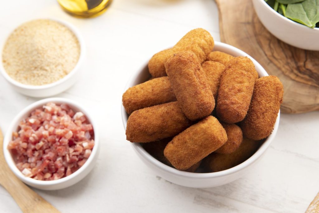 Petiscos de aniversário: confira receitas | Foto de uma mesa com croquetes de calabresa, calabresa picada e farinha | Atacadão