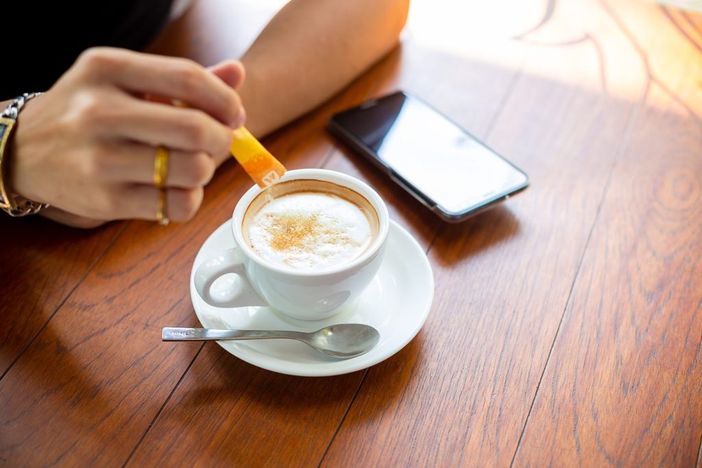 5 dicas para diminuir o açúcar na dieta | Mão colocando açúcar no café | Atacadão