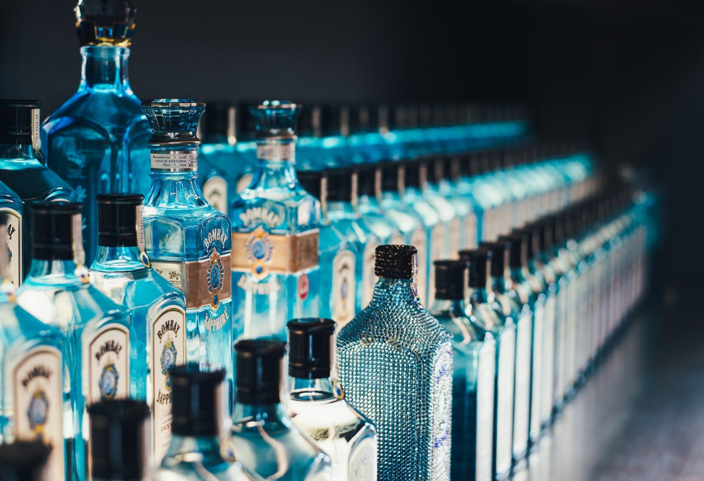 Melhores marcas de gin para vender | Garrafas do gin Bombay Sapphire enfileiradas | Atacadão
