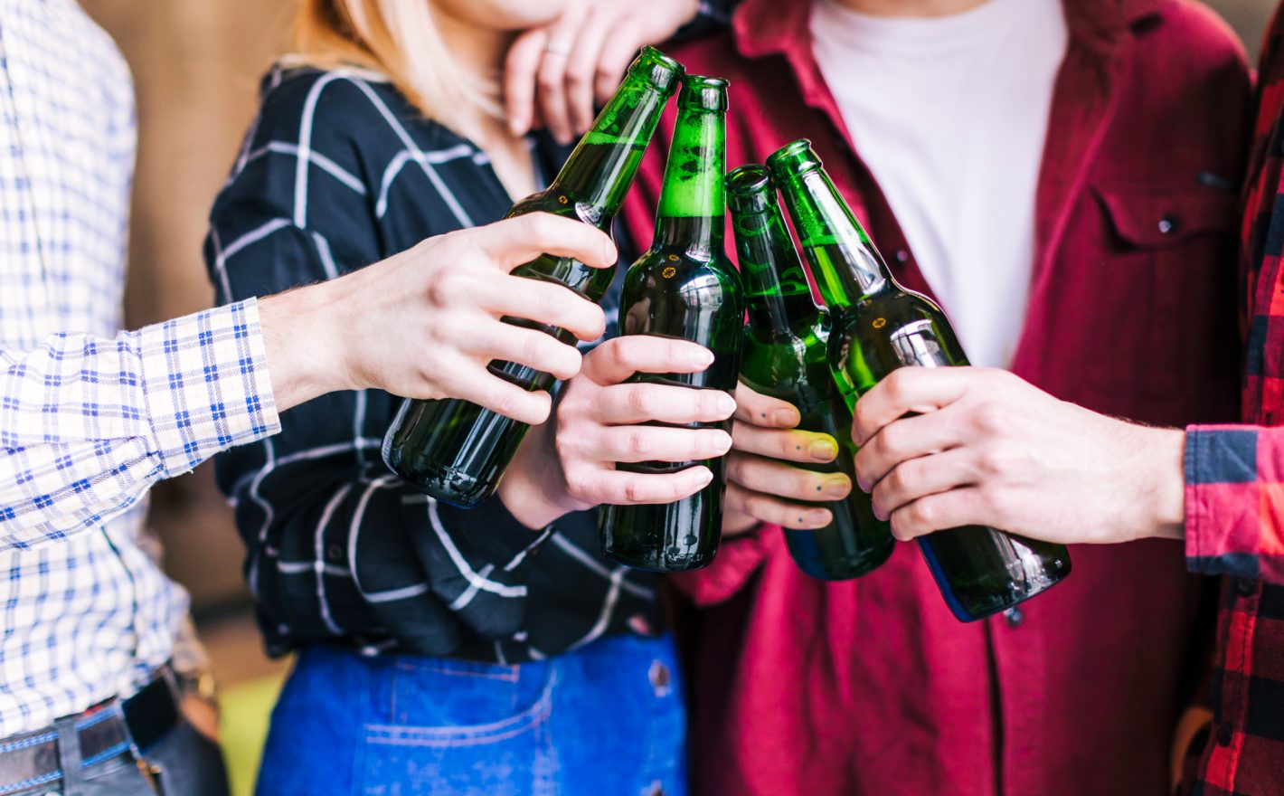 As melhores dicas para comprar bebidas no atacado | Foto mãos brindando com garrafas de cerveja. | Atacadão